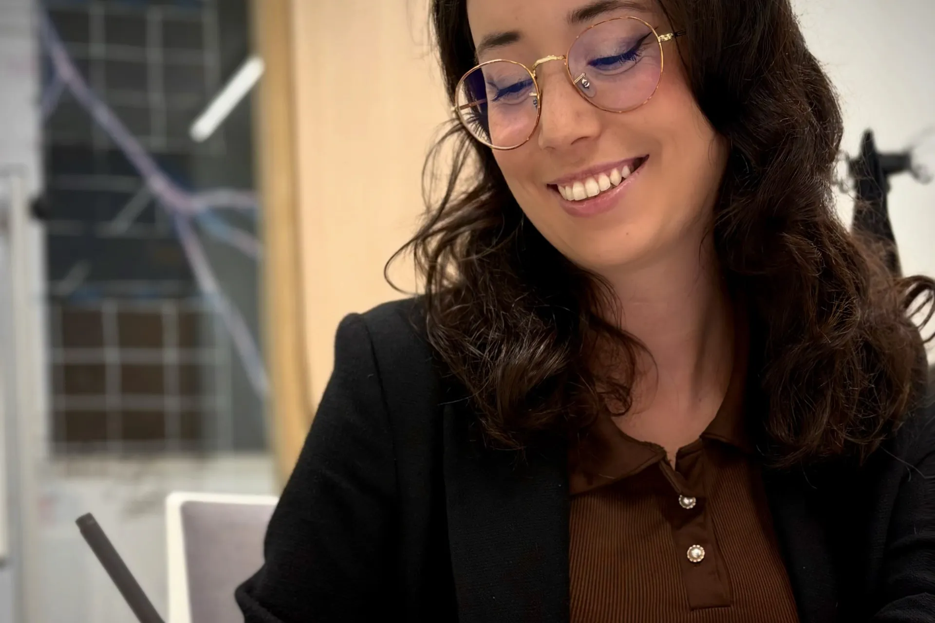 Laure Angelucci, graphiste, souriante à son bureau, un stylo à la main