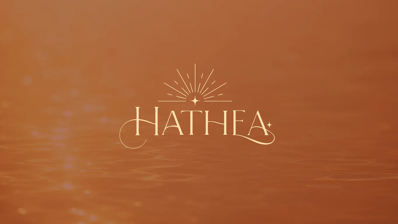 Le mot-symbole HATHEA en crème sur un fond terracotta, surmonté d’une couronne solaire centrée sur une étoile ; un paraphe prolonge le H, un autre le dernier A, et une petite étoile suit la dernière lettre