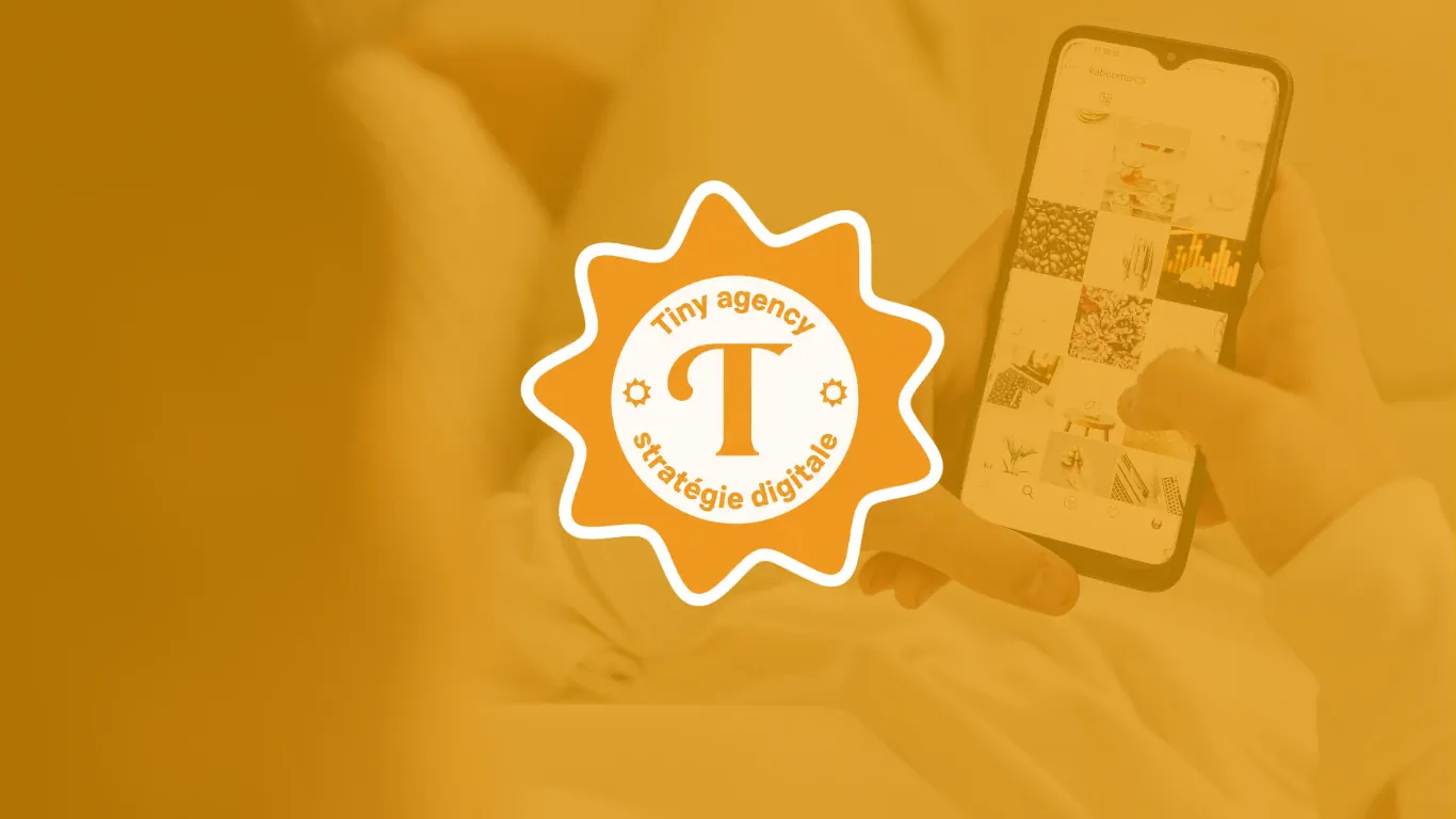 Le badge de Tiny Agency, une étoile orange à douze pointes arrondies portant un T entouré des mots « Tiny agency » et « stratégie digitale », posé sur la photo voilée d’orange d’une main qui fait défiler un fil Instagram sur un téléphone